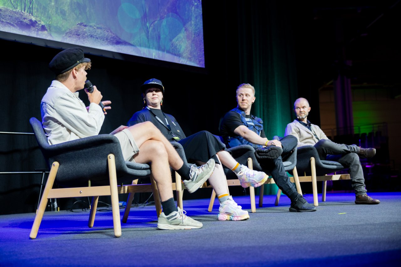 Tubettaja Herbalisti kysymässä kysymystä paneelikeskusteluun osallistuvilta asiantuntijoilta.